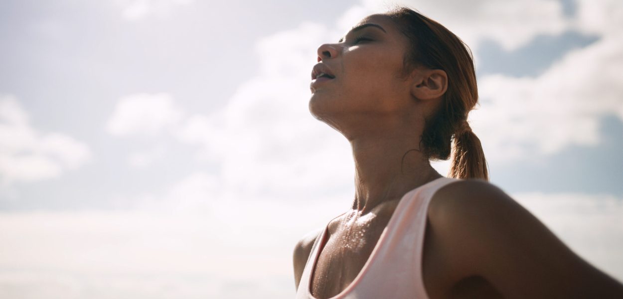 Outdoor, woman and running break with sweat or breathe for fitness, health and self care. Female person, sky and tired or exhausted with jogging as workout, training and exercise for wellness.